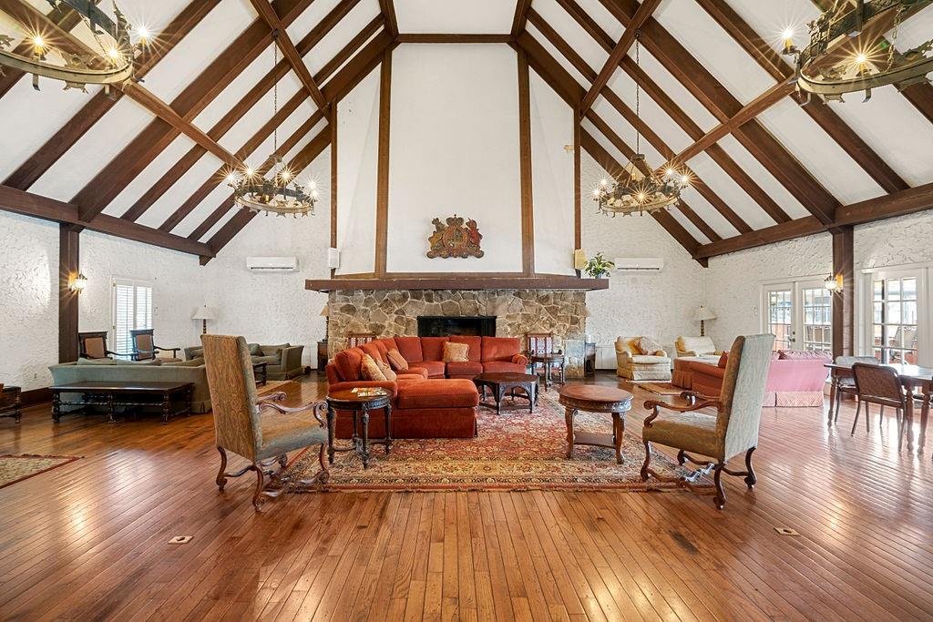 Living room featuring beam ceiling, dark hardwood / wood-style flooring, a notable chandelier, and high vaulted ceiling Living room featuring beam ceiling, dark hardwood / wood-style flooring, a notable chandelier, and high vaulted ceiling
