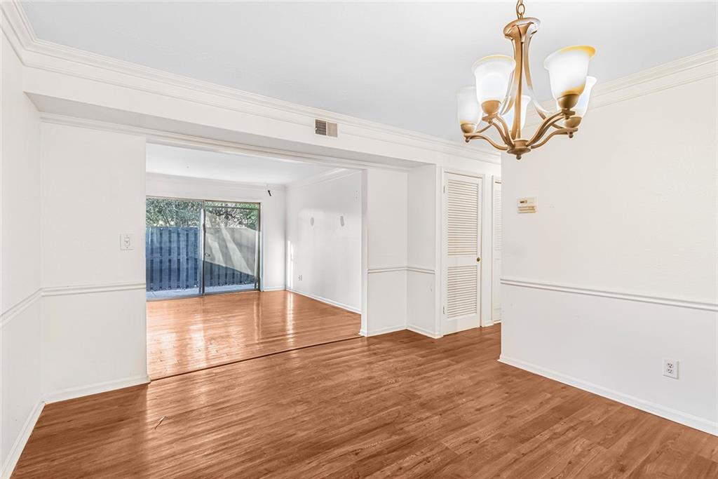Empty room with ornamental molding, a notable chandelier, and hardwood / wood-style flooring Empty room with ornamental molding, a notable chandelier, and hardwood / wood-style flooring