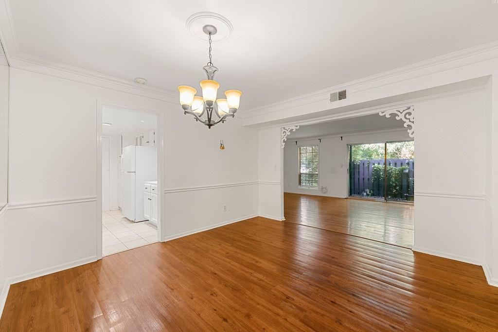 Spare room featuring a chandelier, crown molding, and light hardwood / wood-style floors Spare room featuring a chandelier, crown molding, and light hardwood / wood-style floors