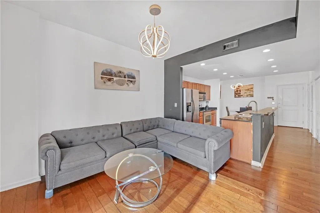 Living room with an inviting chandelier, sink, and light hardwood / wood-style floors