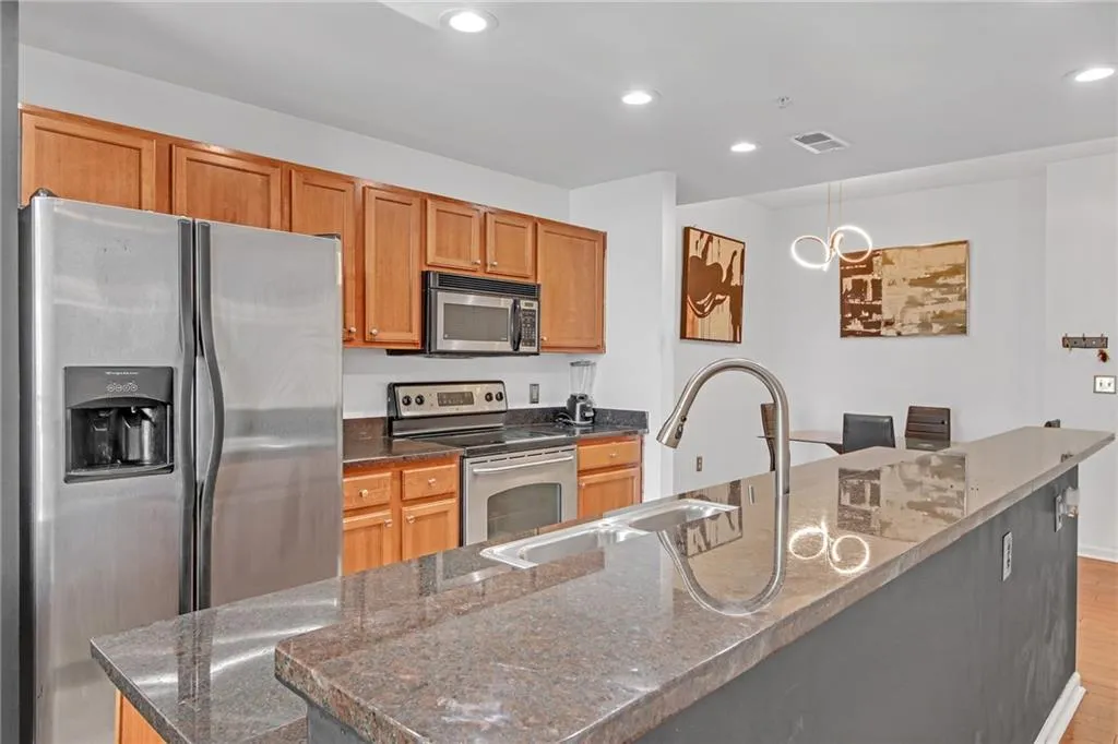 Kitchen with stainless steel appliances, sink, a large island with sink, and dark stone counters