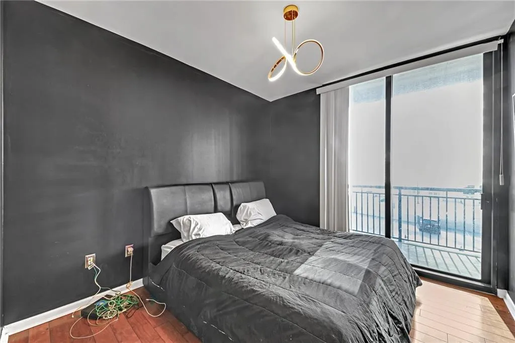 Bedroom with a water view, a wall of windows, and hardwood / wood-style flooring