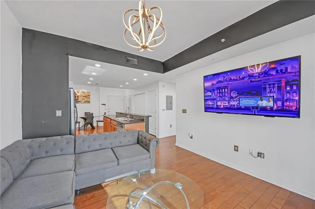 Living room with wood-type flooring, sink, and a notable chandelier