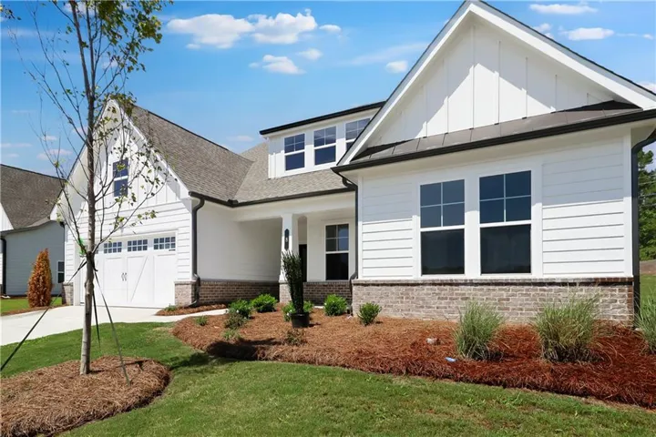 Contemporary white siding exterior featuring a prominent gable, contrasting dark roofline, and a brick foundation