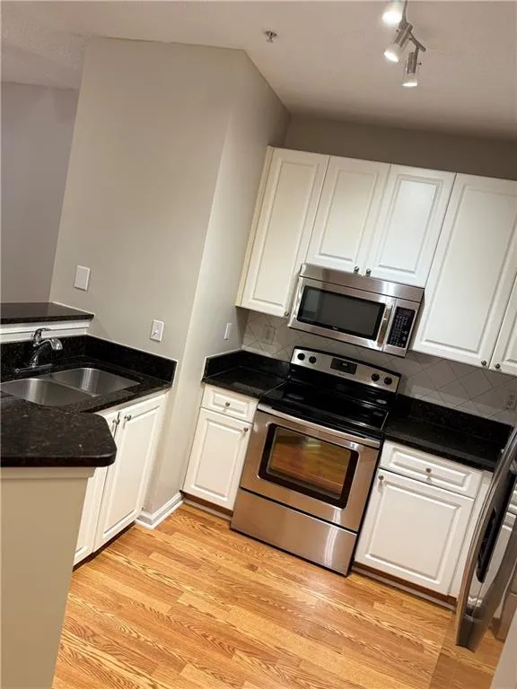 Kitchen featuring stainless steel appliances, white cabinetry, and light wood-type flooring