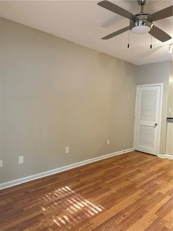 Spare room with wood finished floors and a ceiling fan