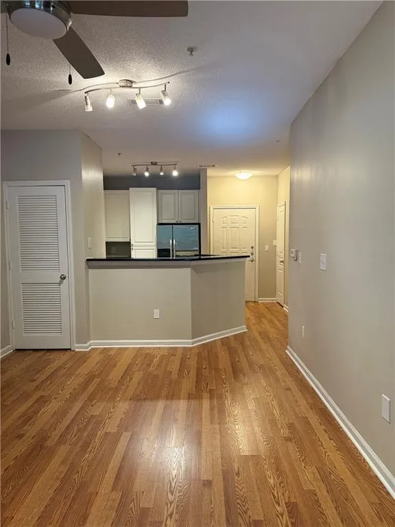 Kitchen featuring stainless steel fridge, dark countertops, and light wood-type flooring