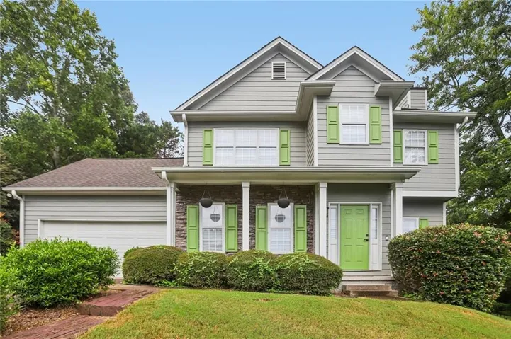 Two-story residence featuring light gray siding, a prominent front porch with white columns, and a bright green front door