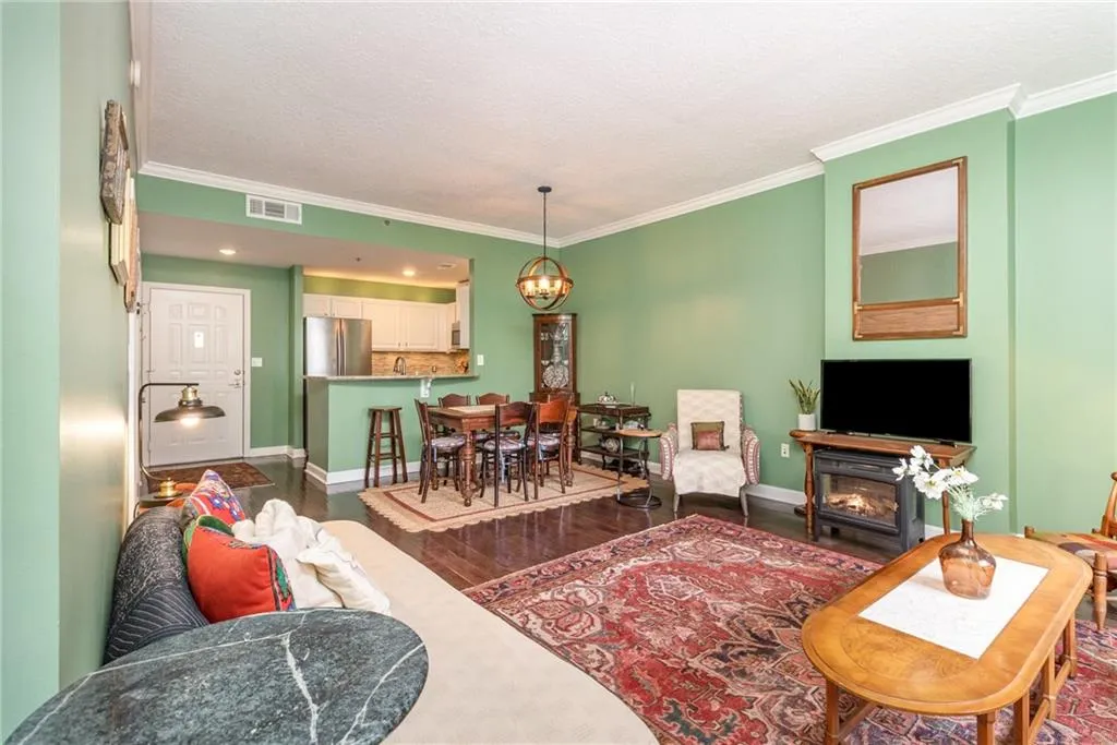 Living area featuring ornamental molding, dark wood-style flooring, a chandelier, a glass covered fireplace, and a textured ceiling