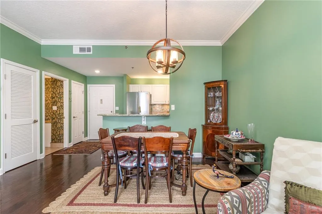 Dining room with dark wood-style flooring, a textured ceiling, a chandelier, and crown molding