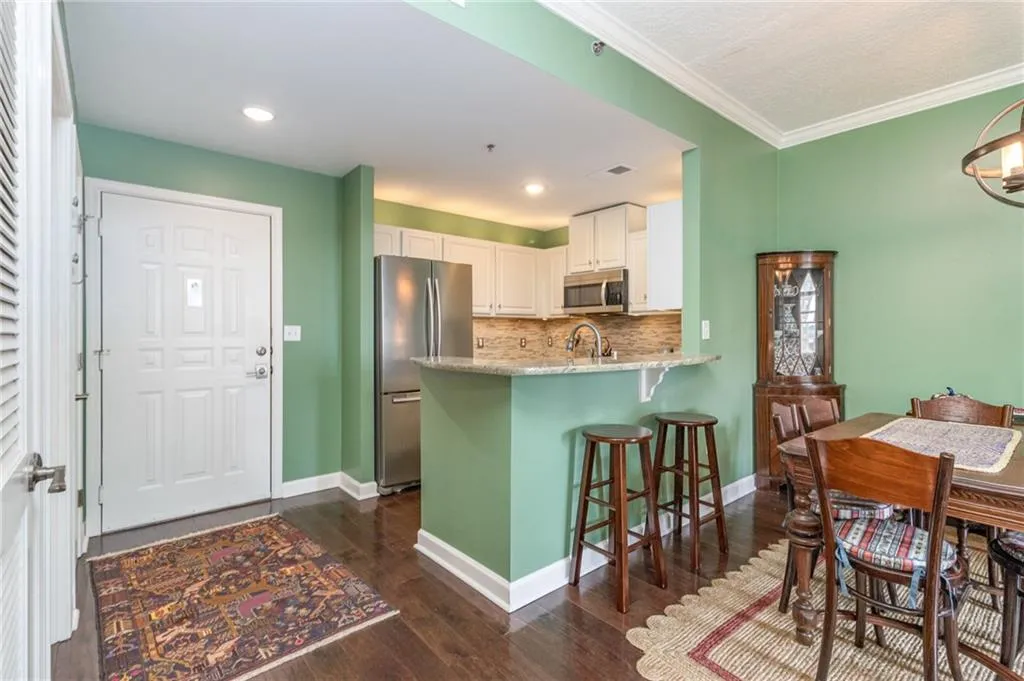 Kitchen with appliances with stainless steel finishes, white cabinetry, decorative backsplash, a breakfast bar, and dark wood-style floors