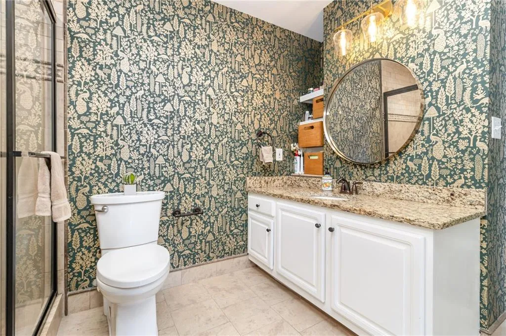 Bathroom with wallpapered walls, vanity, light tile patterned floors, and a stall shower