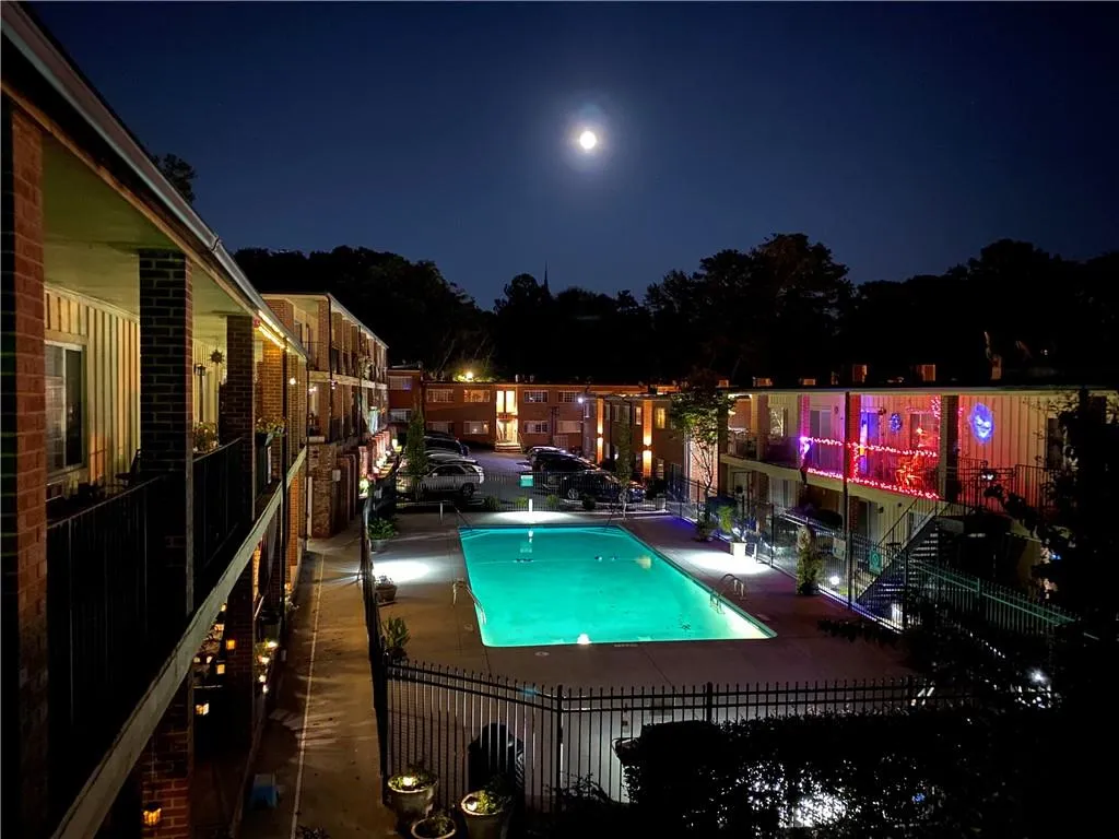 Pool at night featuring a patio area and a community pool