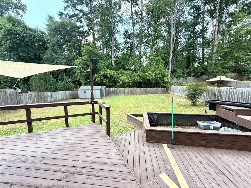 Deck featuring a storage unit, a fenced backyard, and view of scattered trees
