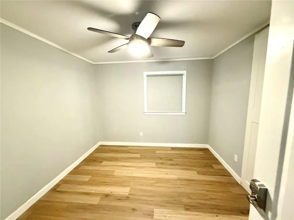 Spare room with a ceiling fan, light wood-style floors, and ornamental molding
