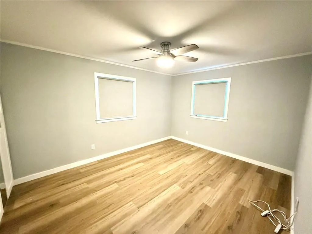 Unfurnished room with ornamental molding, ceiling fan, and light wood-style flooring