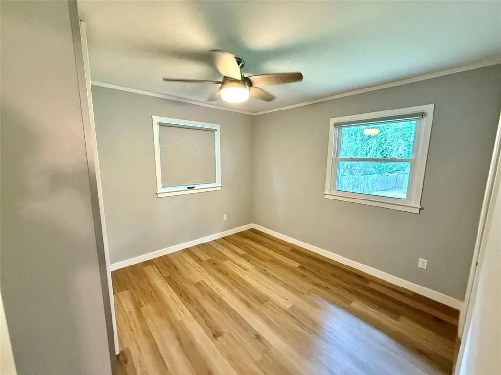 Unfurnished room featuring ornamental molding, light wood-style floors, and a ceiling fan
