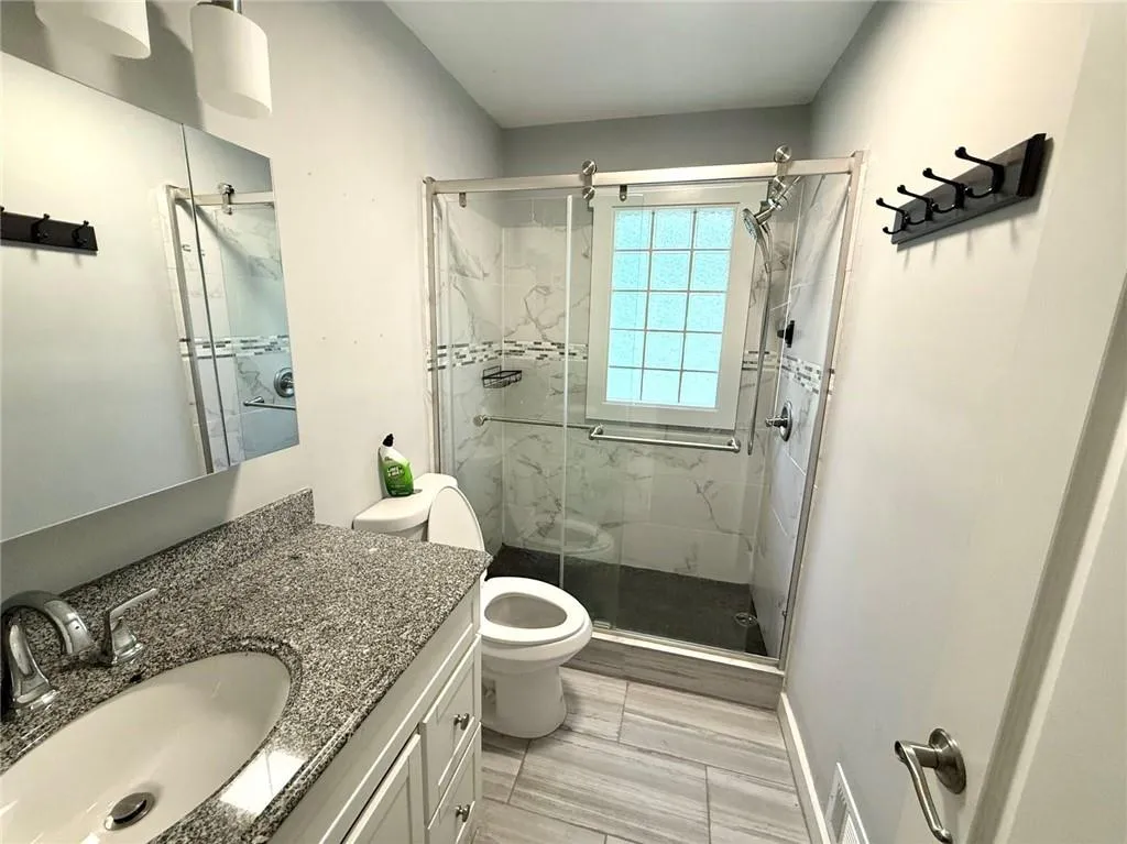 Full bath featuring vanity and a marble finish shower