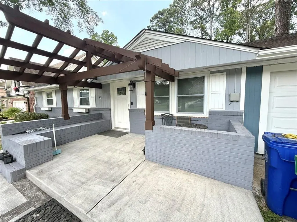 Entrance to property featuring a pergola and brick siding