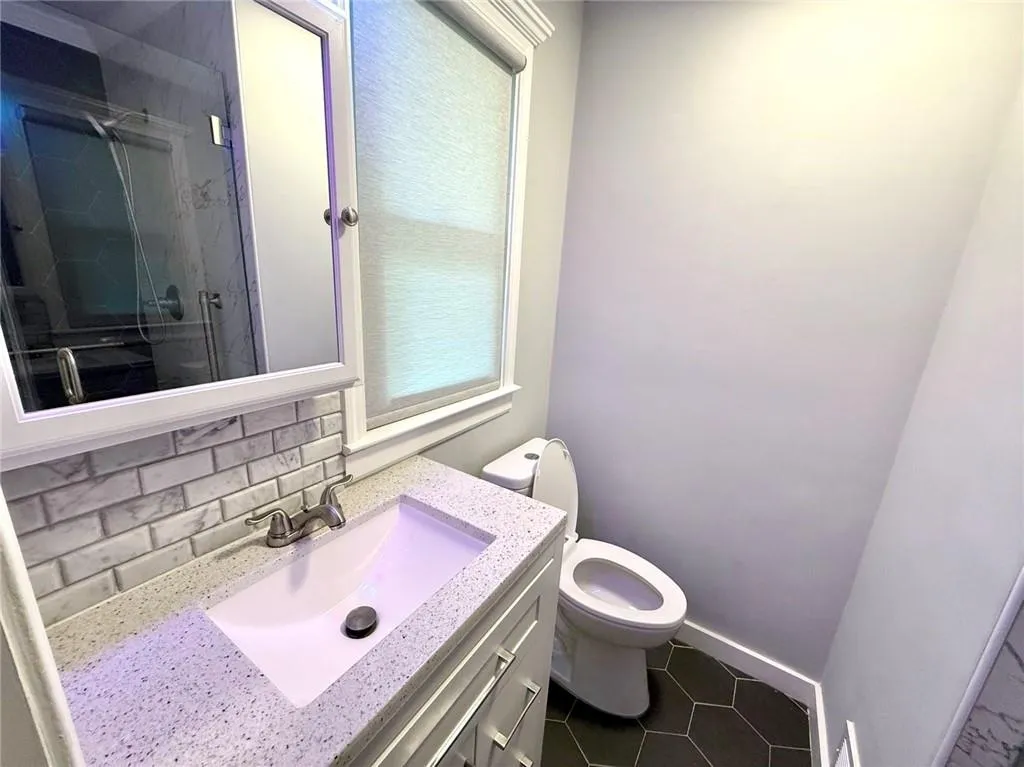 Bathroom with vanity, a shower stall, tile patterned floors, and decorative backsplash