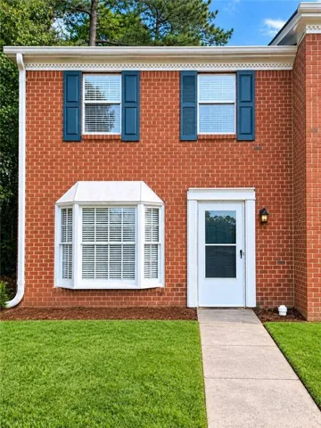 Brick exterior with a prominent bay window, white front door, and dark blue decorative shutters
