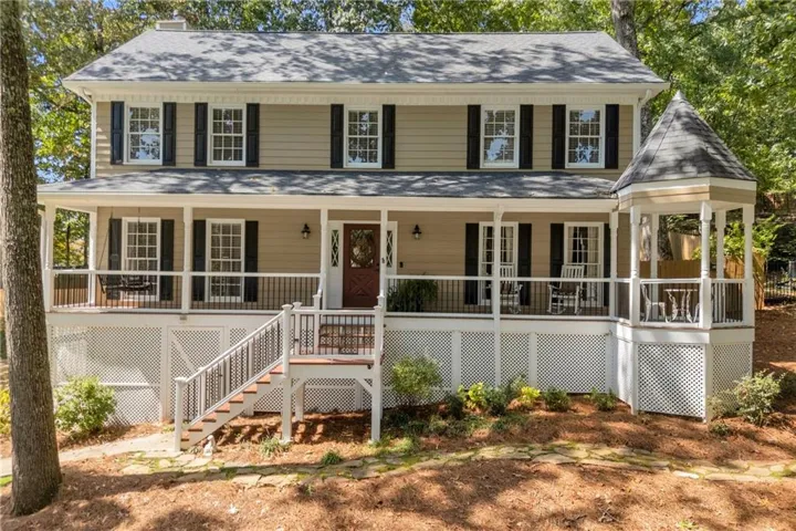Two-story exterior with a covered porch, white lattice skirting, and a gazebo