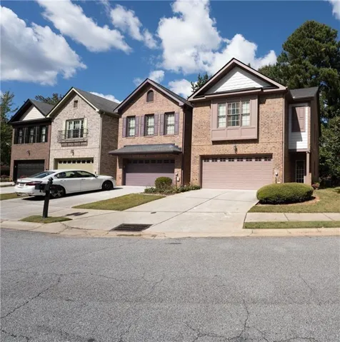 Brick exterior, two-story structure, attached garage, concrete driveway, and landscaping