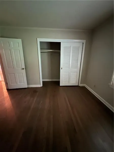Unfurnished bedroom with dark wood-type flooring, a closet, and ornamental molding