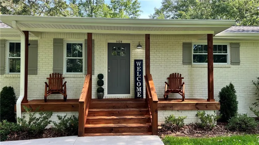 Doorway to property featuring covered porch and brick siding
