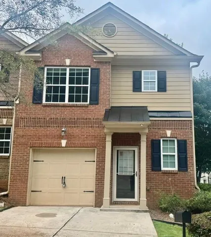 Brick and siding exterior with dark shutters, covered entry with columns, and an integrated garage