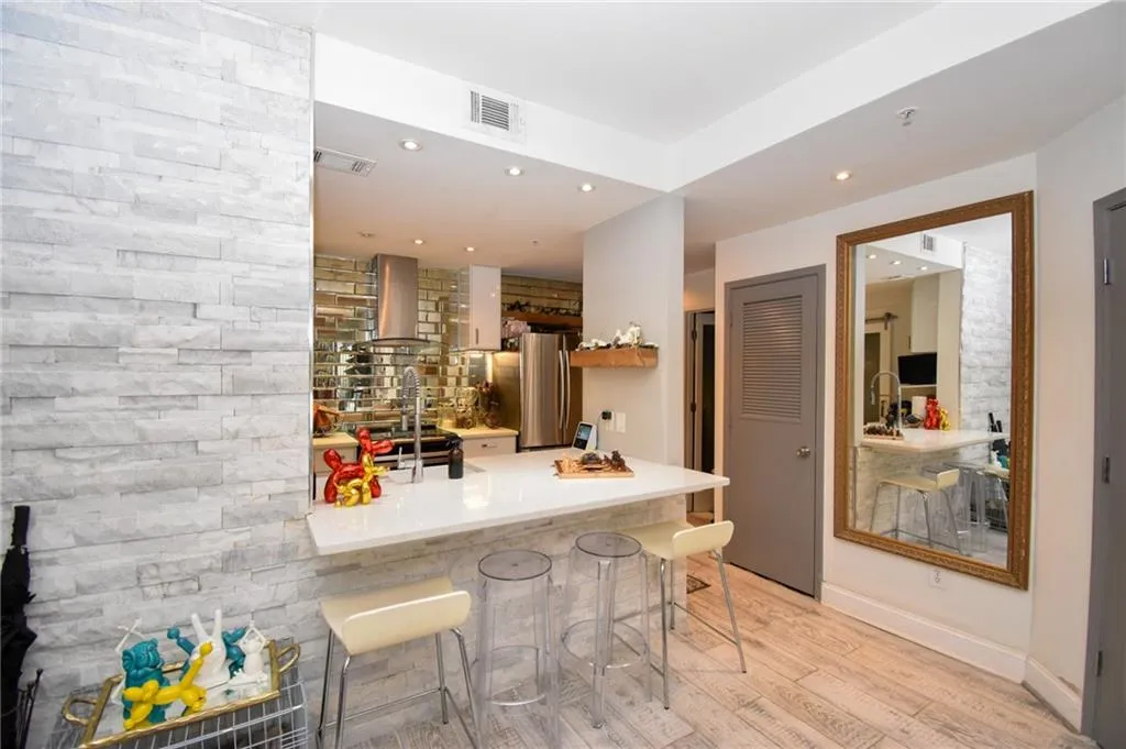 Bar with light wood-style floors, recessed lighting, wall chimney exhaust hood, freestanding refrigerator, and light stone counters