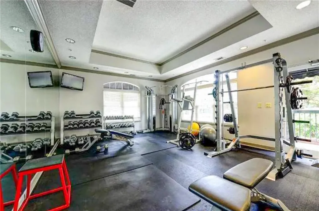 Gym with a raised ceiling, crown molding, a textured ceiling, healthy amount of natural light, and recessed lighting