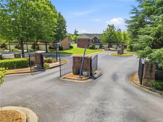Gated community entrance with brick columns and black wrought iron gates