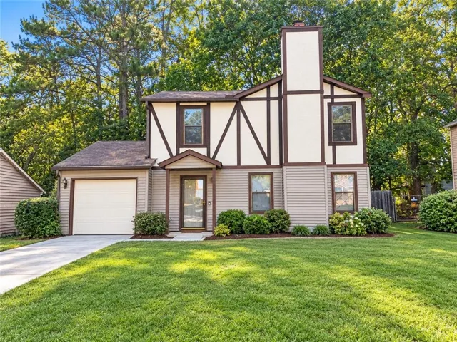 Two-story exterior with Tudor-style accents, an attached single-car garage, covered entry, and a concrete driveway