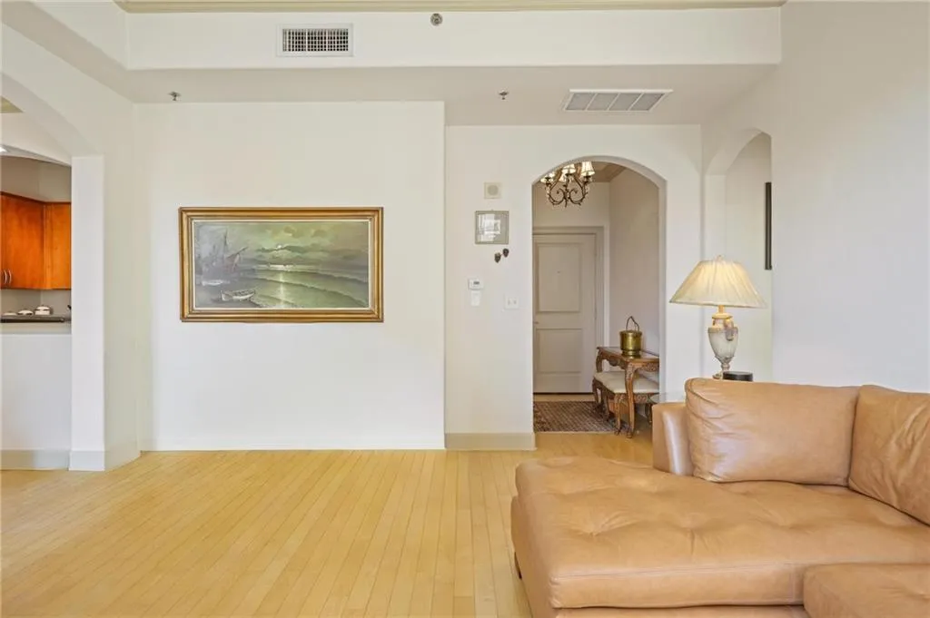Living room featuring arched walkways, light wood finished floors, and a chandelier