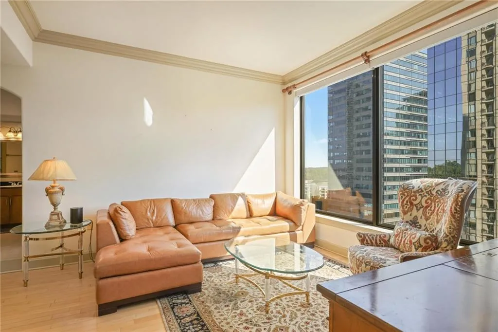 Living room featuring crown molding, light wood finished floors, arched walkways, and a view of city
