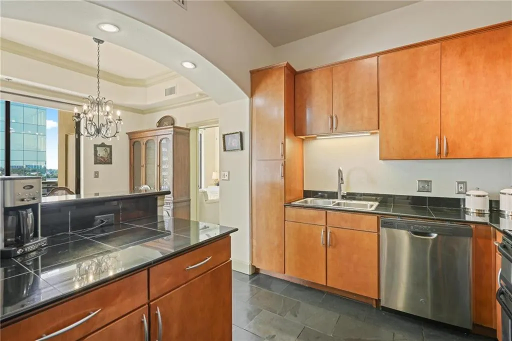 Kitchen with a tray ceiling, dishwasher, pendant lighting, tile countertops, and crown molding