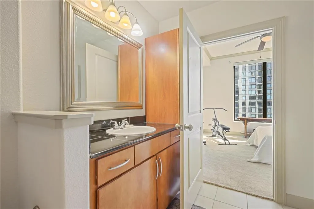 Half bathroom featuring vanity, light tile patterned floors, ceiling fan, and connected bathroom
