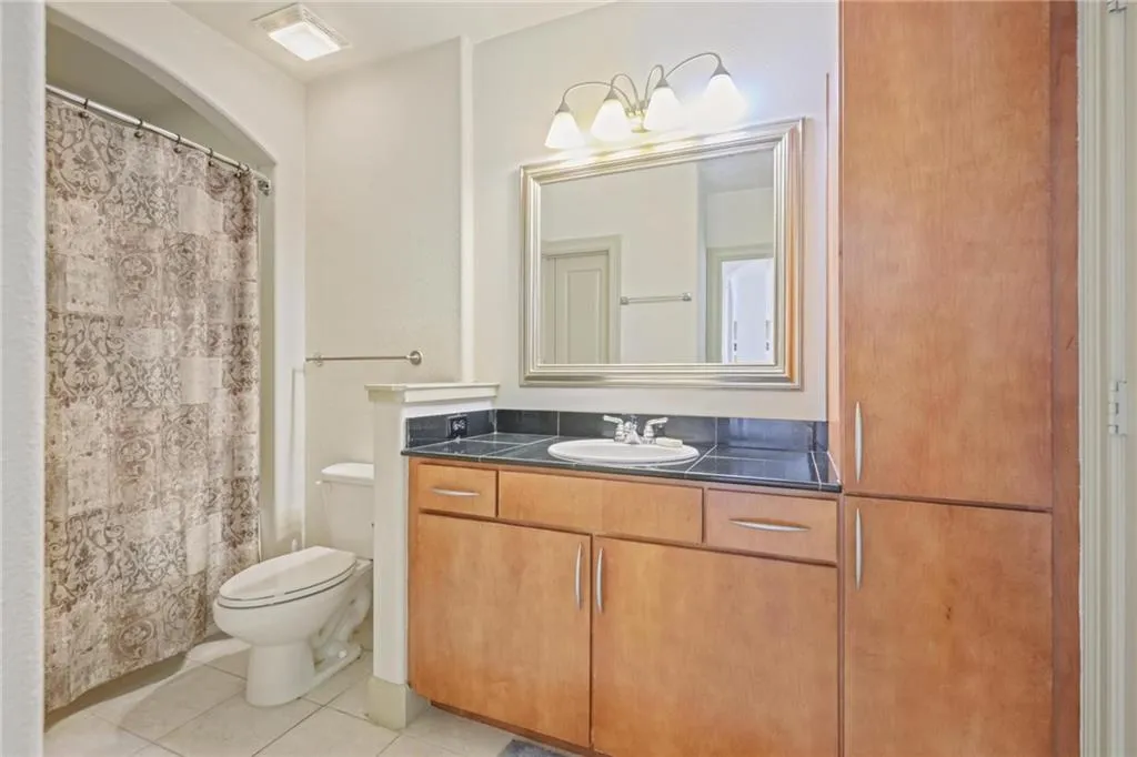 Bathroom featuring light tile patterned floors, vanity, and curtained shower