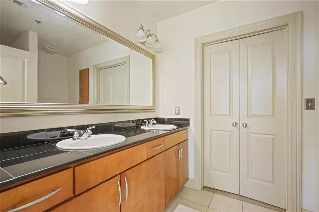 Bathroom with light tile patterned flooring, double vanity, and a closet