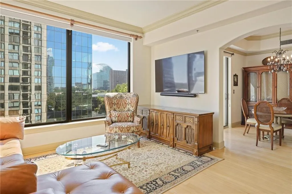 Living area with crown molding, a chandelier, wood finished floors, and arched walkways