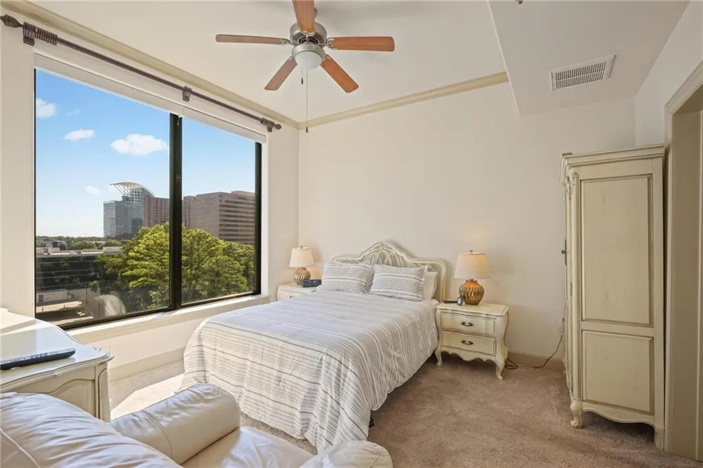 Bedroom featuring carpet flooring, a view of city, crown molding, and ceiling fan