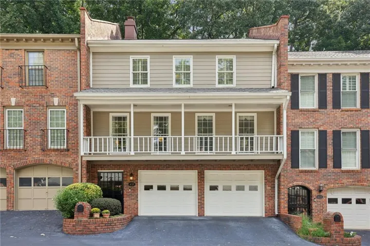 Brick townhouse with a two-car garage, upper balcony, and siding facade