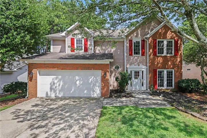 Traditional exterior featuring brick and siding, a two-car garage, and red window shutters