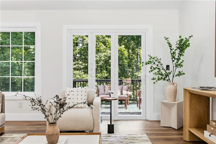 Hardwood flooring, white window frames, glass-paned sliding door, balcony access, and white wall finishes
