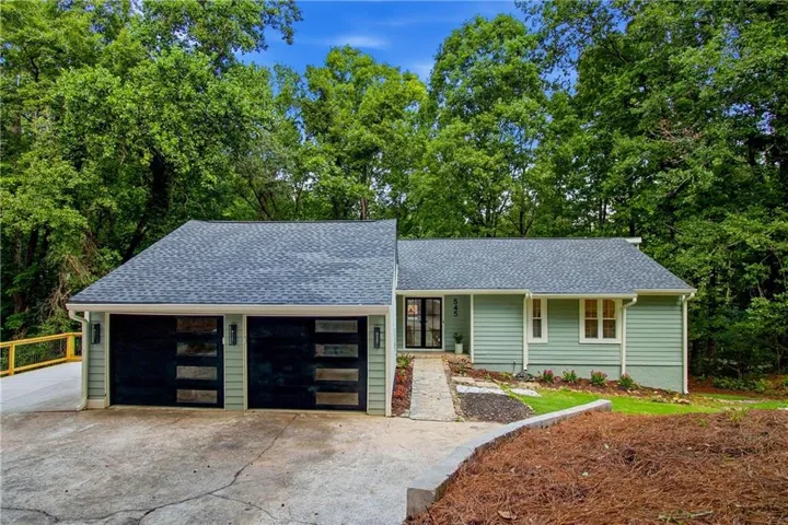 Siding exterior with a dark-pitched roof, modern garage doors, and a stone-finish walkway leading to the entrance