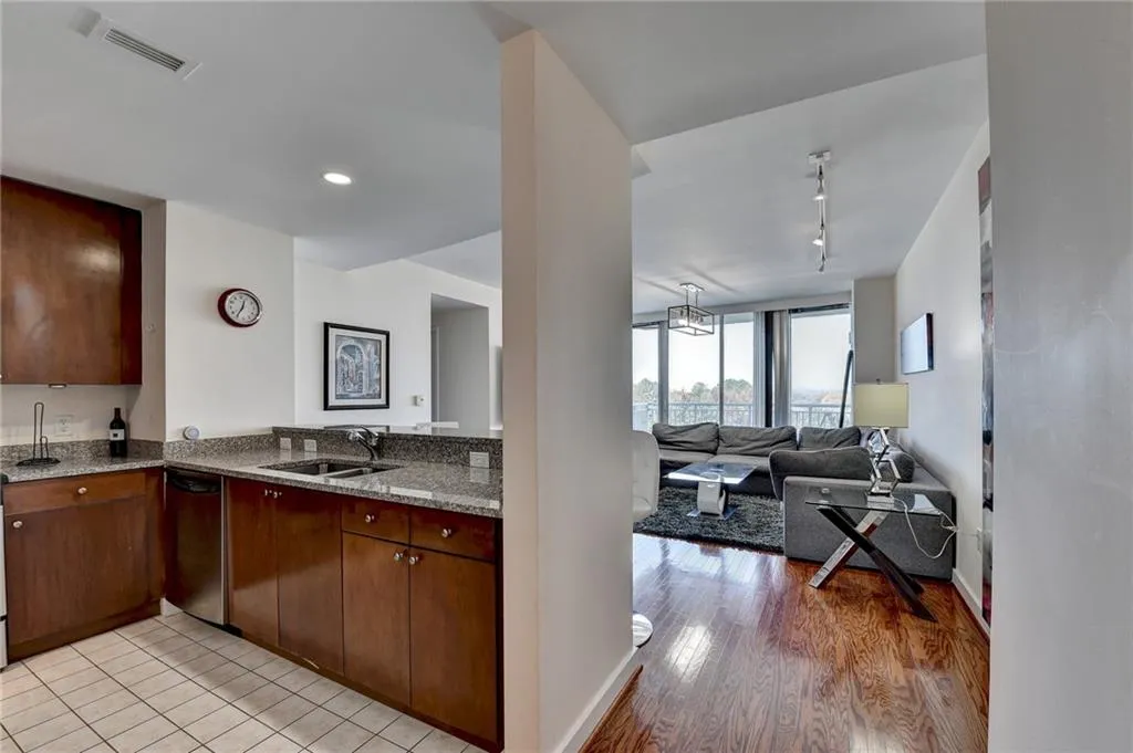 Kitchen featuring dishwasher, track lighting, sink, light stone countertops, and light wood-type flooring