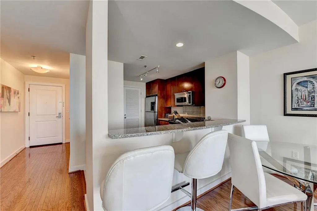 Kitchen with kitchen peninsula, appliances with stainless steel finishes, light wood-type flooring, a kitchen bar, and light stone counters