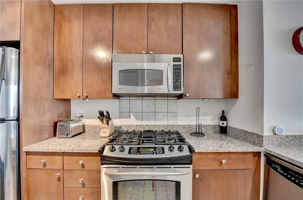 Kitchen featuring appliances with stainless steel finishes and light stone counters