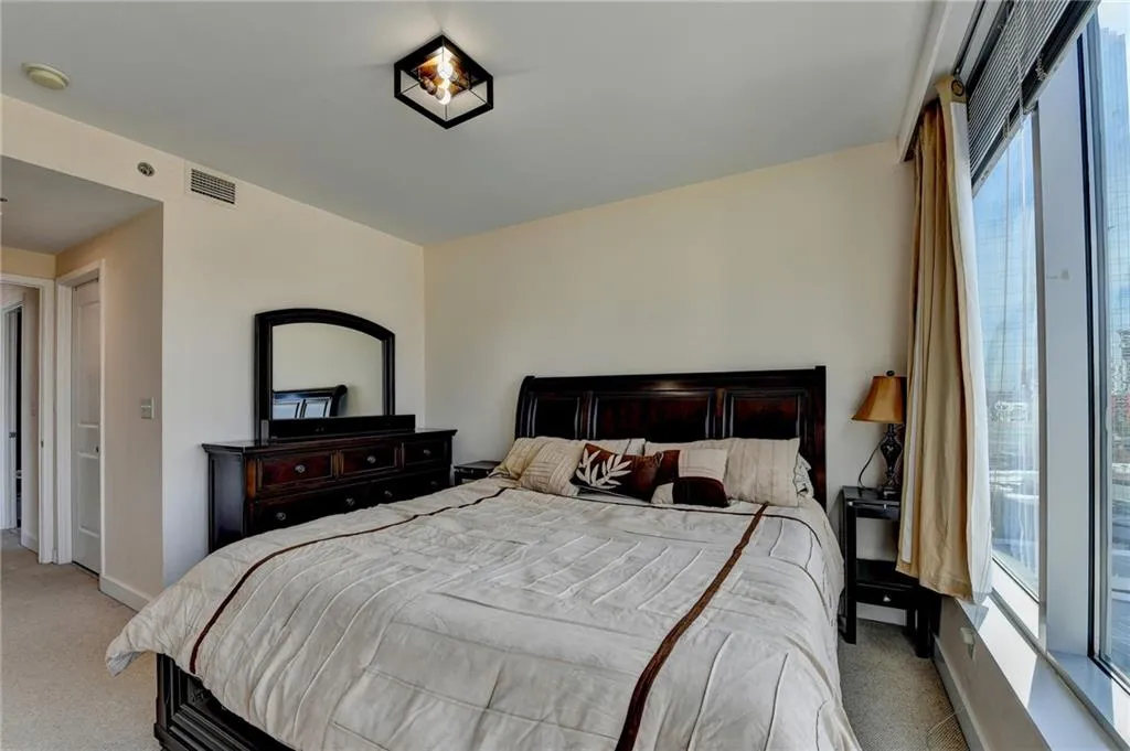 Bedroom featuring light carpet and multiple windows